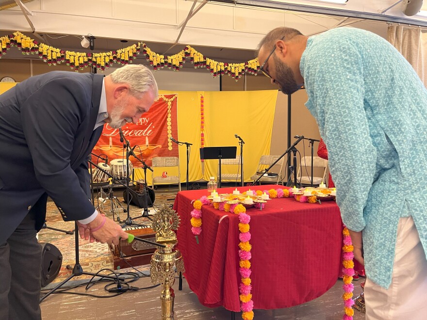 Concord Mayor Byron Champlin lights a traditional oil lamp, or panas, as Suraj Budathoki looks on.