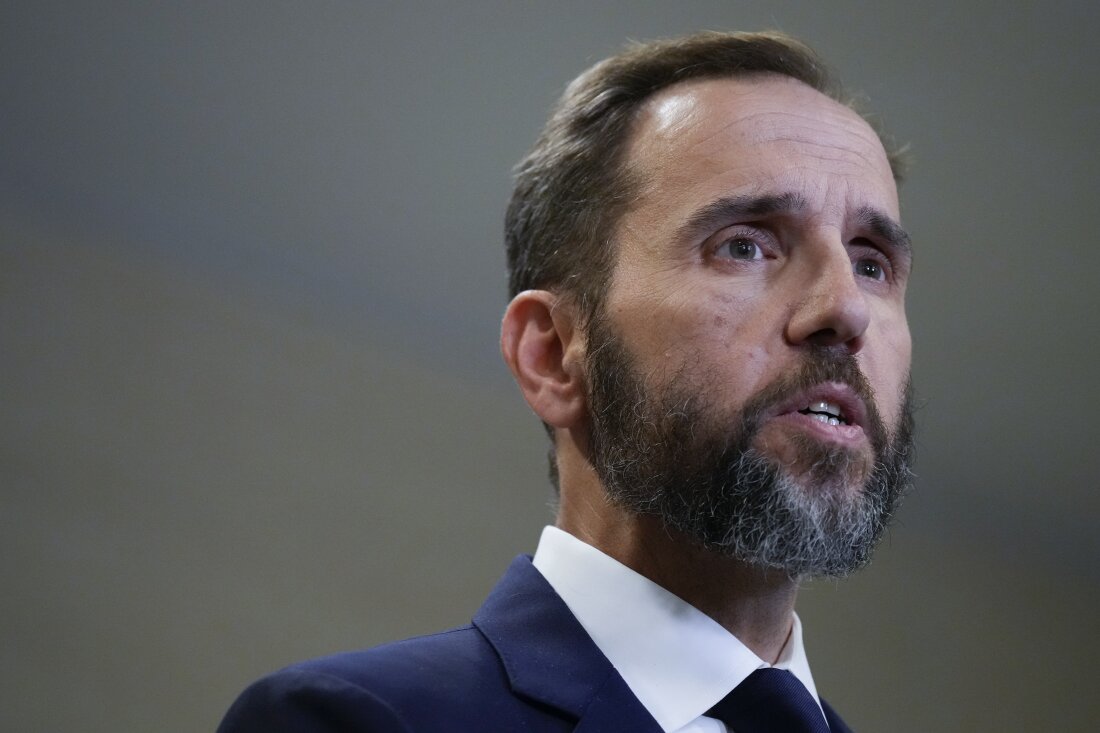 This photo shows special counsel Jack Smith from the shoulders up in August 2023. He has brown hair, including a beard, and is wearing a white shirt, blue suit jacket and dark tie.