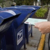 A person drops applications for mail-in-ballots into a mailbox in 2020 in Omaha, Neb.