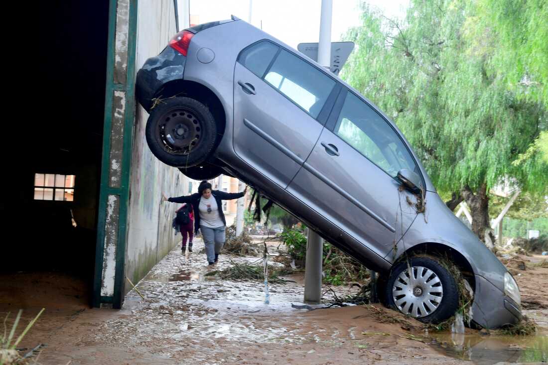 TOPSHOT - A resident walks next to a car lifted up in a street covered in mud in a flooded area in Picanya, near Valencia, eastern Spain, on October 30, 2024. Floods triggered by torrential rains in Spain's eastern Valencia region has left 51 people dead, rescue services said on October 30. (Photo by Jose Jordan / AFP) (Photo by JOSE JORDAN/AFP via Getty Images)