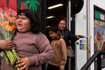 (from left) Rosa, Angel and Sinforosa Avelino leave with their bouquets of cempasúchil purchased from Colima Market in Bend, Ore., on Oct. 30, 2024.