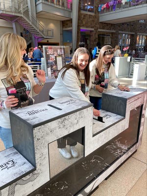 From left, Swifties Kourtney Holbrook, Jenny Sugg and Courtney Holbrook drop notecards inscribed with fears and regrets including "Not getting tickets" into a Reputation-themed paper shredder at the Indiana State Museum's TAY/Gate party on Nov. 1, 2024.