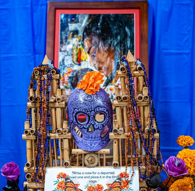 With artwork in the background, this community ofrenda featuring a place to write a note to a passed loved one at the Dia de los Muertos event at the State of Michigan Library Friday, Nov. 1, 2024. The event presented by Casa de Rosado Galeria and Cultural Center features over a dozen ofrendas made by the community.