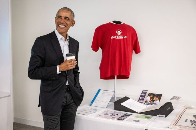 Former President Barack Obama poses with Iowa caucus artifacts that will be displayed in the Obama Presidential Center.