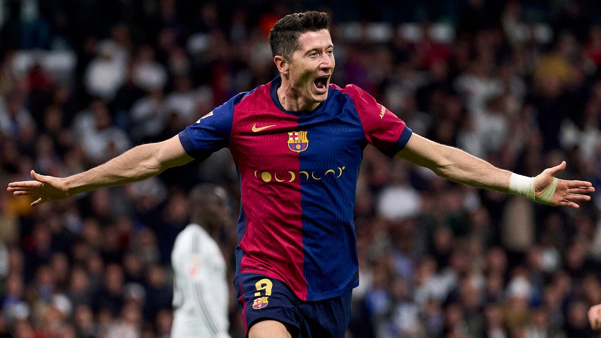 Barcelona striker Robert Lewandowski celebrating , running, with both arms outstretched.