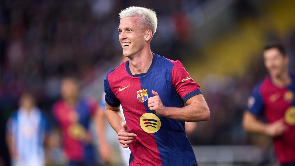 Barcelona forward Dani Olmo running, smiling, looking over to his right.