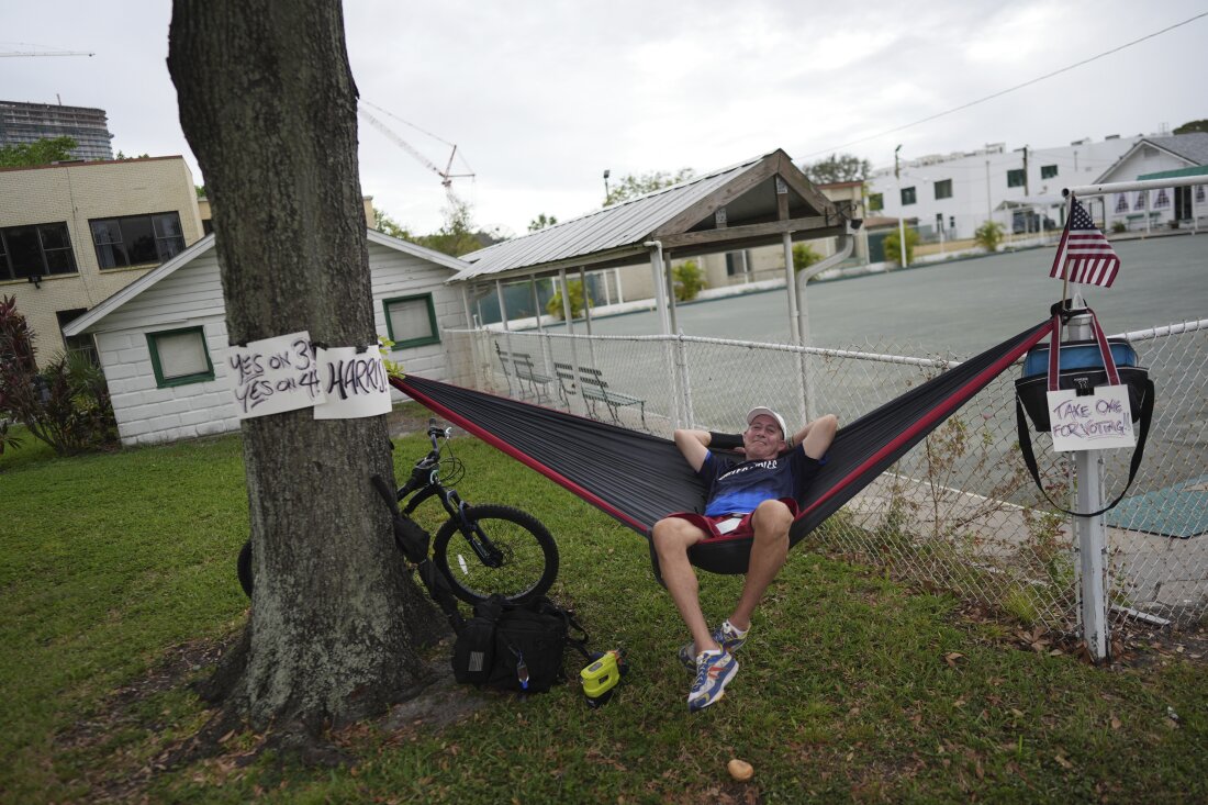 Christopher Reid, 54, a U.S. Army veteran, relaxes in a hammock alongside homemade signs supporting Democratic presidential nominee Vice President Kamala Harris and Florida's Amendments 3 and 4, which would legalize recreational marijuana and enshrine abortion rights in the state, respectively, across from a polling place at the Coliseum in downtown St. Petersburg, Florida on Tuesday.