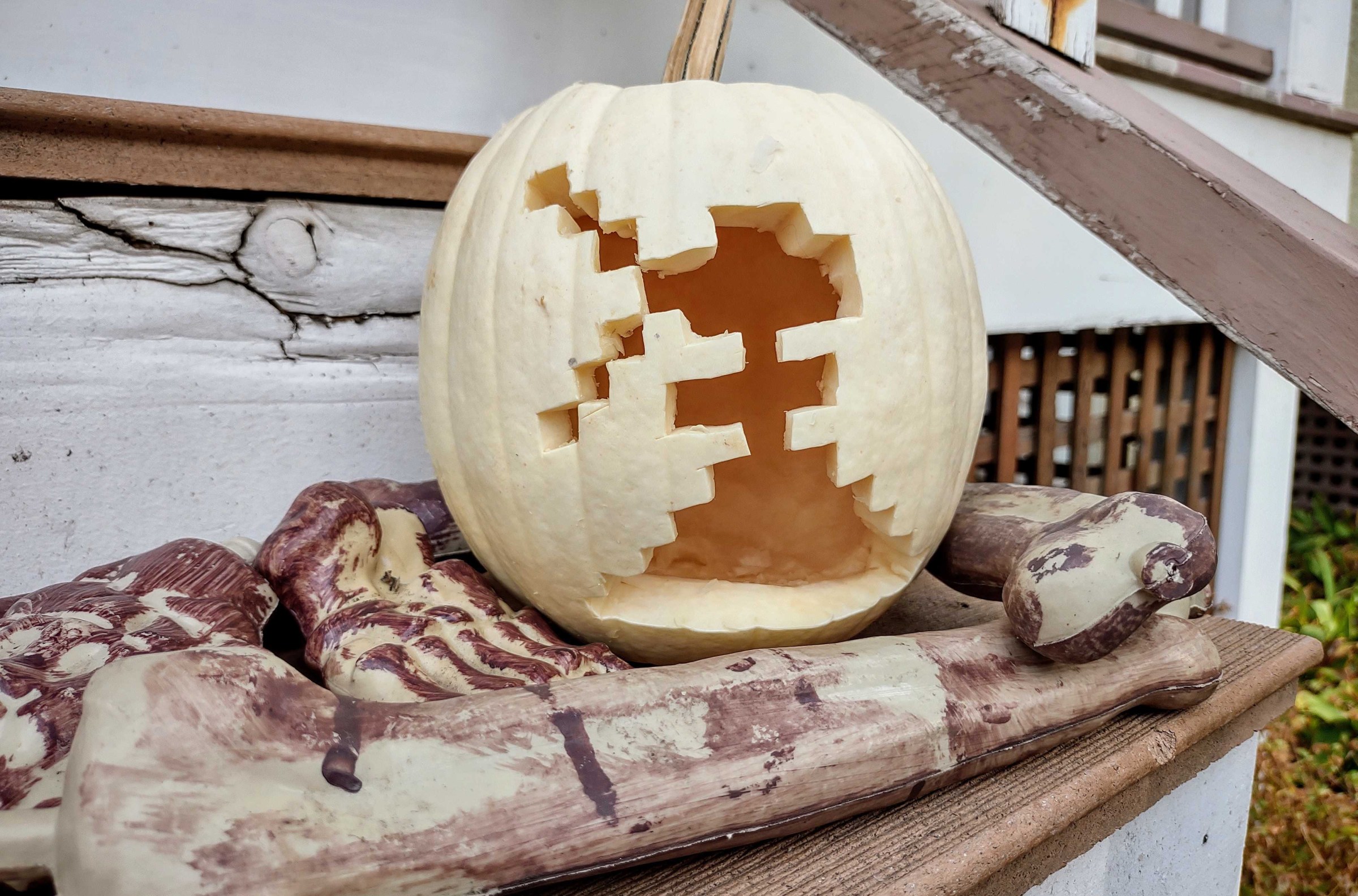 An 8-bit, pixelated figure is carved into the surface of a white pumpkin. 