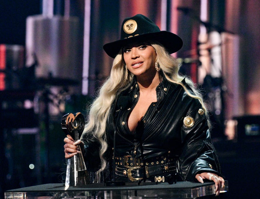 beyonce wearing a cowboy hat and holding a trophy behind a podium